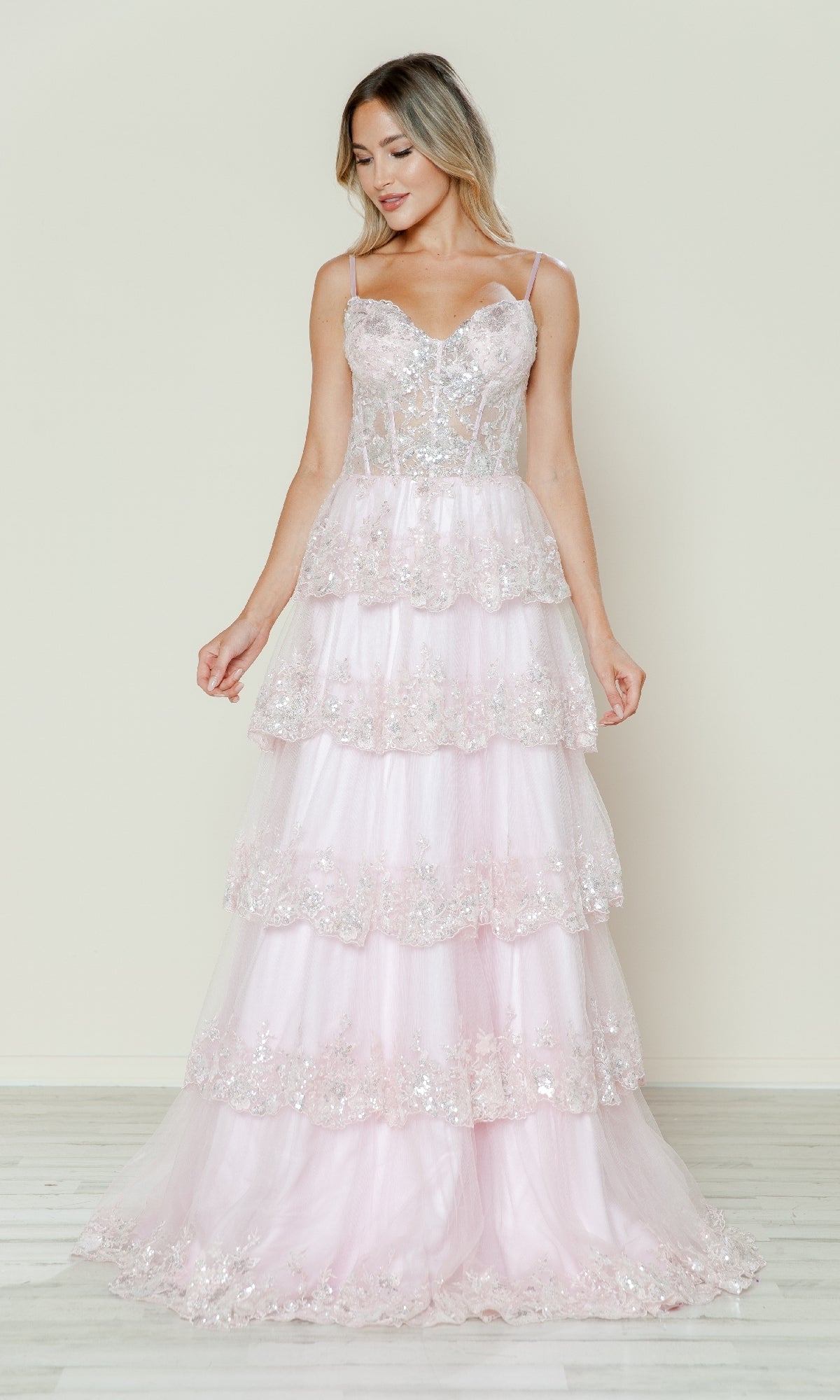 A woman wears the Long Glitter-Lace Tiered Prom Dress (Poly USA 9548) in blush—a sleeveless, spaghetti-strap gown with floral lace embellishments—standing against a plain light background.